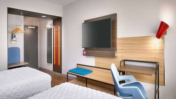Habitación de hotel con dos camas, un televisor, un escritorio y una silla.