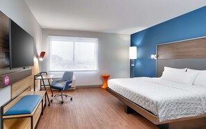 A hotel room with a bed, a desk with a chair, a TV, a window with a view, and a lamp. - TRU by Hilton Lehi, UT (Lehi)