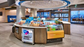 Een moderne hotellobby met een centraal gelegen balie, een zithoek en grote ramen met uitzicht over de stad.