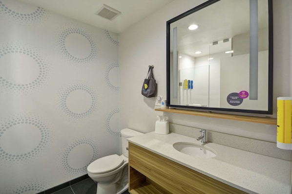 A modern bathroom with a toilet, sink, and mirror. - TRU By Hilton Winchester (Winchester)