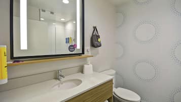 Un bagno moderno con uno specchio grande, un lavandino, un water e un portasciugamani.