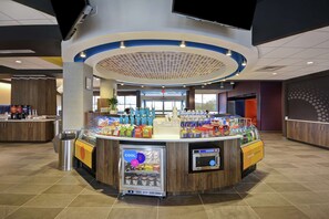Un espace de libre-service proposant une variété de boissons, avec un distributeur de boissons réfrigéré, une machine à café et divers en-cas.