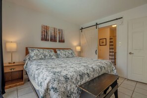 A bedroom with a bed, bedside tables, a bench, a sliding door, and a wall-mounted picture. - Laurel Inn 206 is a beautiful condo with private balcony close to downtown (Gatlinburg)