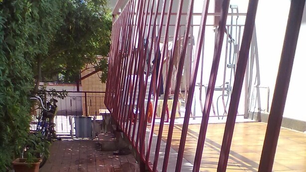 A paved outdoor area with a metal fence, a potted plant, and a bicycle. - Apartment in residence in Mongiove a stone's throw from the sea (Mongiove)