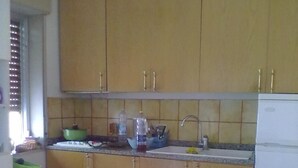 A kitchen with wooden cabinets, a sink, and a table with a yellow tablecloth. - Apartment in residence in Mongiove a stone's throw from the sea (Mongiove)