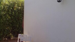 A small outdoor patio with a round table and four white chairs. - Apartment in residence in Mongiove a stone's throw from the sea (Mongiove)