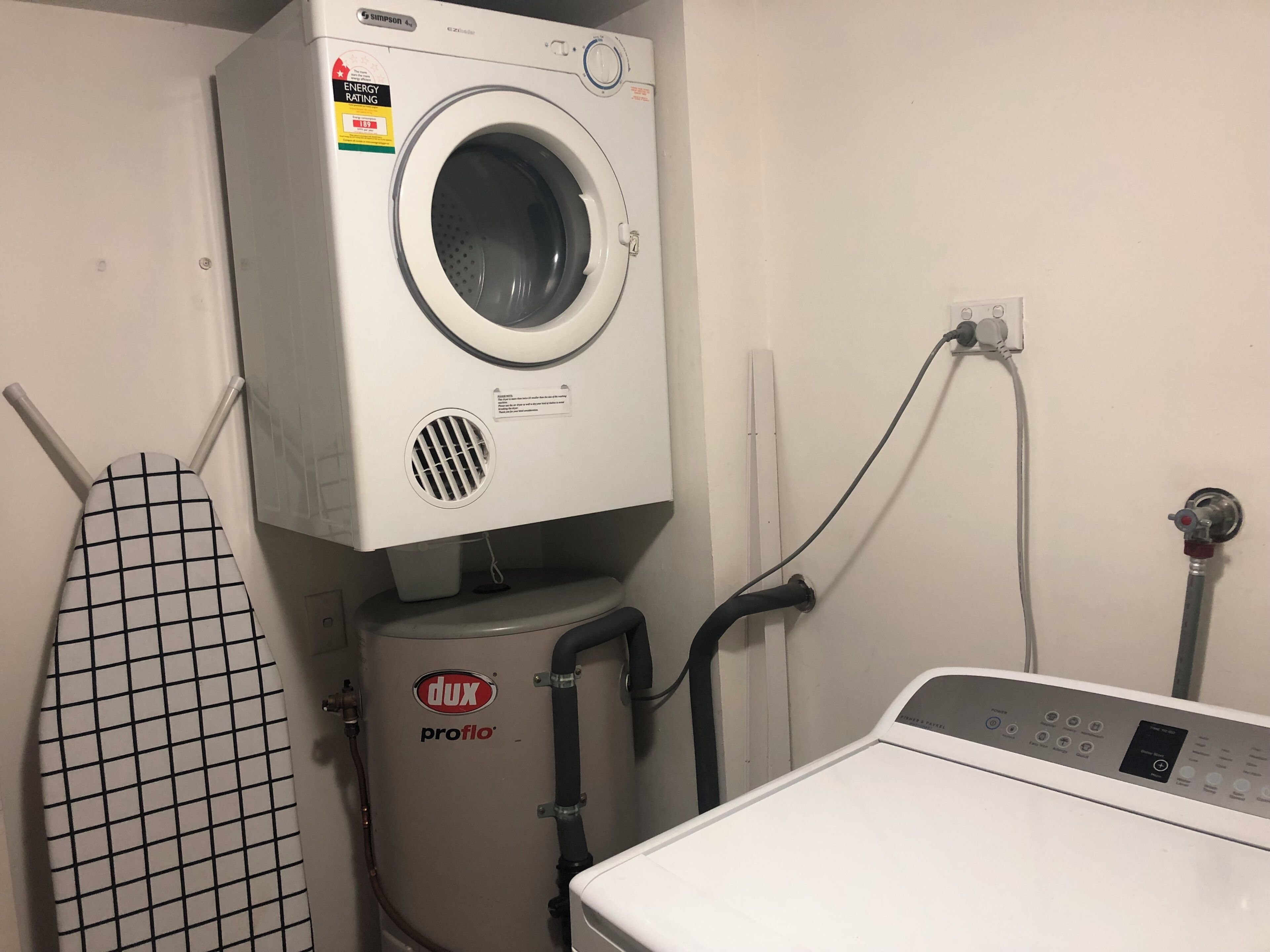 A compact laundry room with a front-loading washing machine, a steam iron, and a water heater.