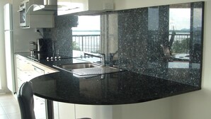 Eine moderne Küche mit einer Granit-Arbeitsplatte, einer Edelstahl-Spüle und einem schwarzen Stuhl.