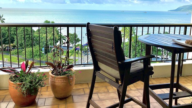 Ein Balkon mit Meerblick, ein Stuhl, ein Tisch und Kübelpflanzen.
