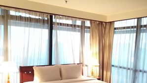 A hotel room with a large bed, two bedside tables with lamps, and a view through sheer curtains. - 1 Ivy Suite At Berjaya Times Square (Kuala Lumpur)