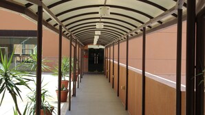 A covered corridor with potted plants, metal columns, and a tiled floor. - 1 Ivy Suite At Berjaya Times Square (Kuala Lumpur)