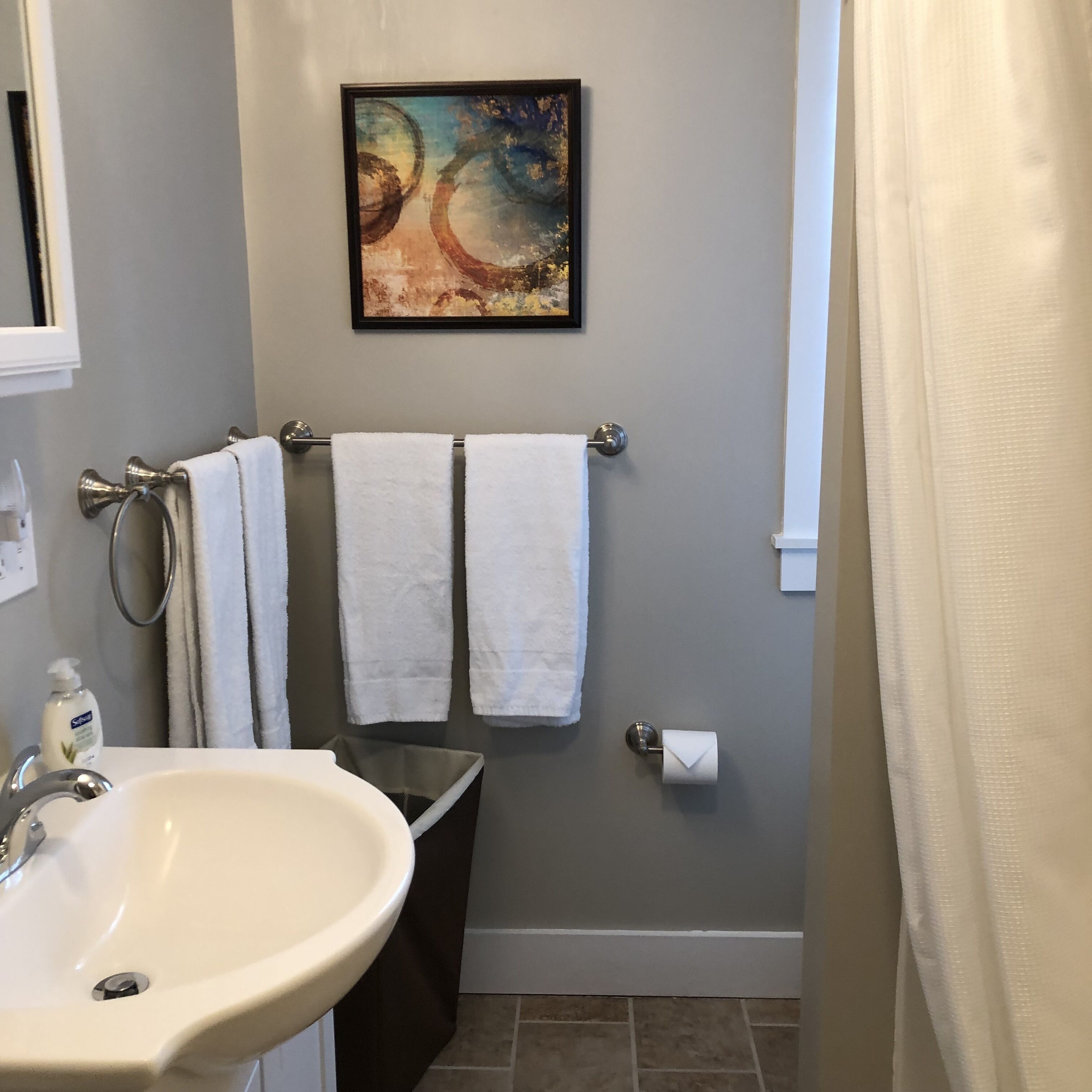 Une salle de bain avec un lavabo, deux serviettes, des toilettes et un tableau encadré au mur.