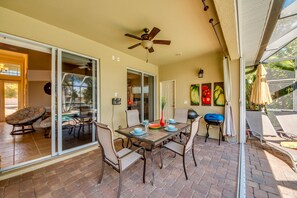 Une terrasse extérieure avec une table à manger, des chaises et un ventilateur de plafond.