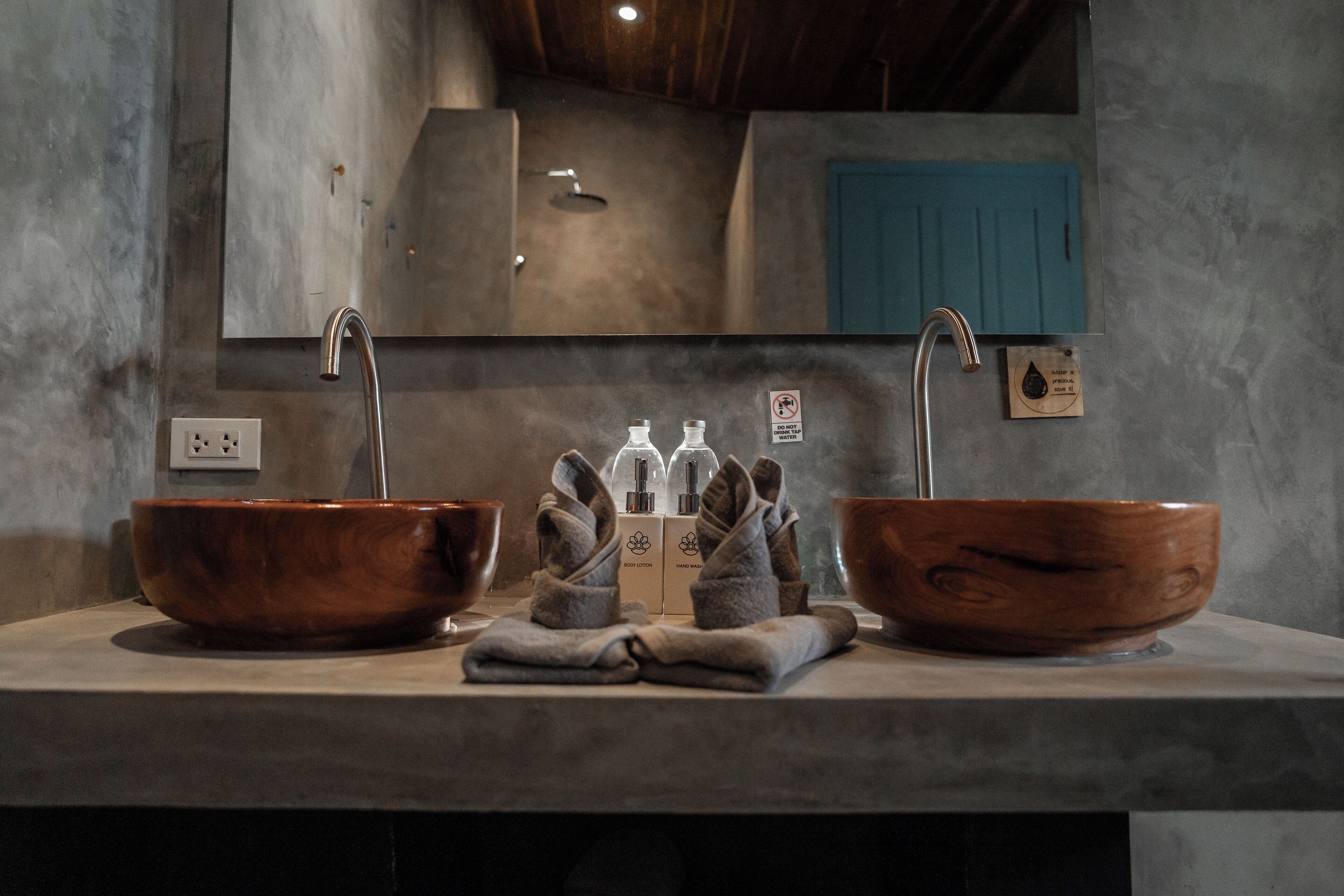 Un baño con dos lavamanos de madera, un espejo y un perchero con toallas dobladas.