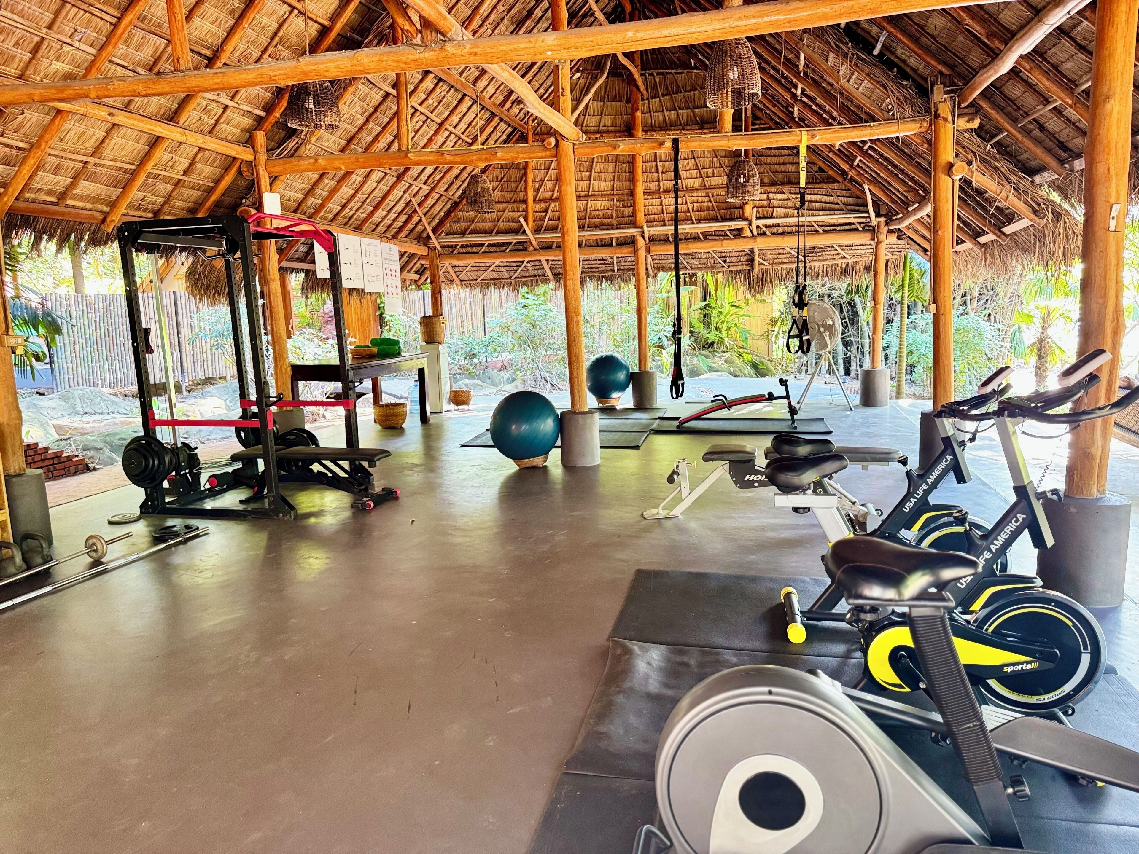 A gym with exercise equipment, including a weight bench, a treadmill, and a stationary bike.