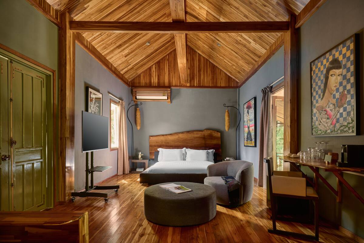 Une chambre spacieuse avec un grand lit, un plafond en bois et une porte verte.