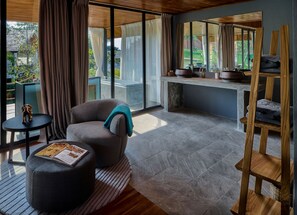 Una sala de estar moderna con un sofá gris, una mesita redonda con una revista y una mesita auxiliar de madera.
