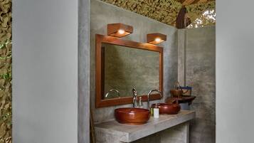 Un baño con un lavabo de concreto, una pileta de madera y un espejo grande.