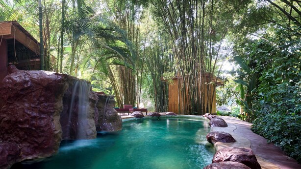 A natural pool with a waterfall, surrounded by bamboo and tropical foliage. - The Namkhan, a Small Luxury Hotel of the World (Luang Prabang)