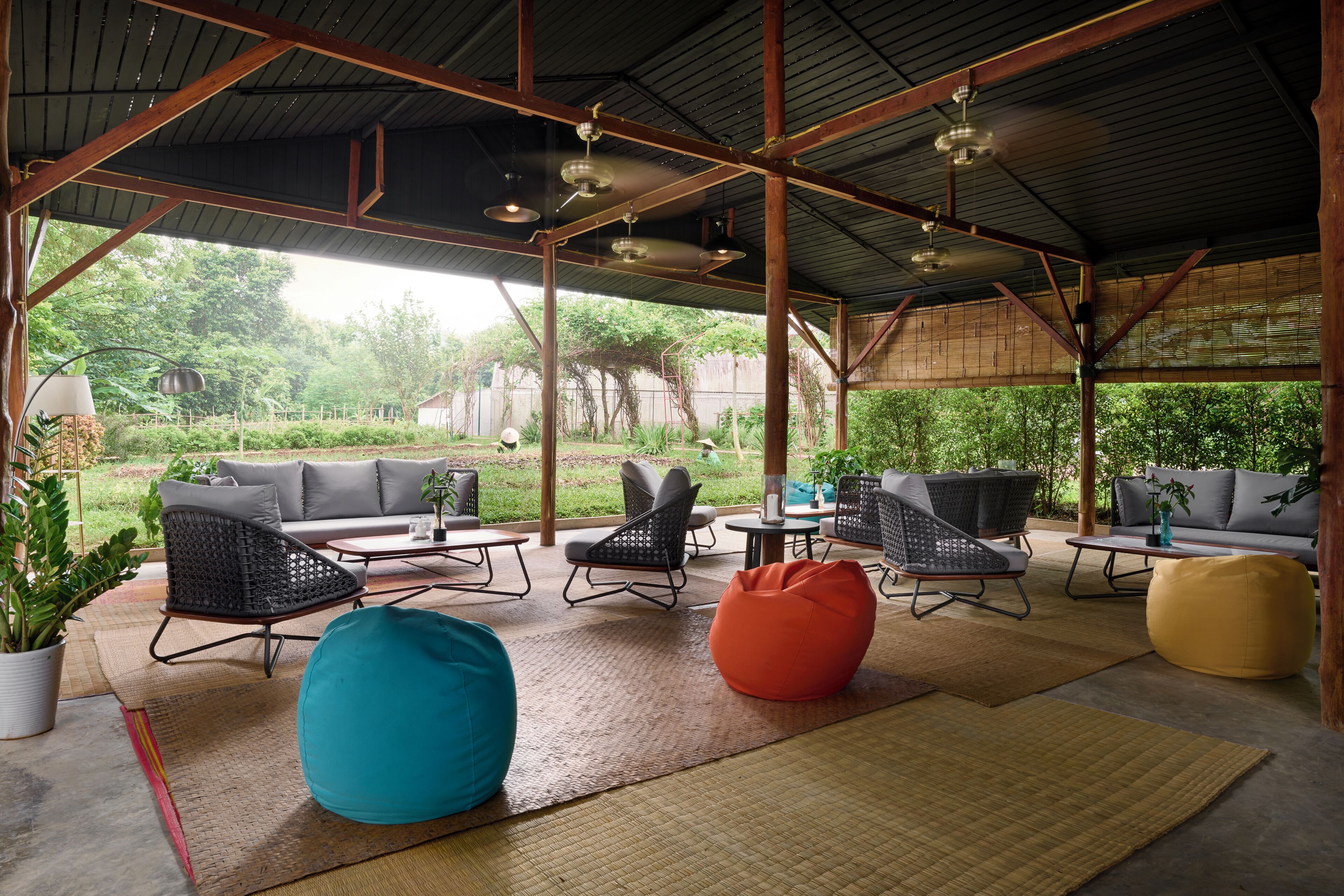 Une terrasse extérieure couverte, aménagée avec des sièges, des tables et offrant une vue sur le jardin.
