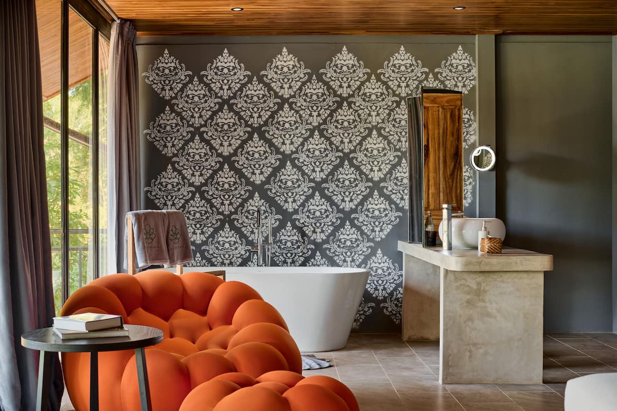 Une salle de bain moderne avec une baignoire sur pieds, un meuble-lavabo avec un miroir et un papier peint à motifs.