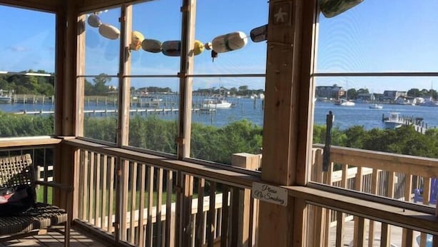 Une terrasse en bois offrant une vue sur un port de plaisance, un panneau indiquant «Il est interdit de fumer» et un banc.