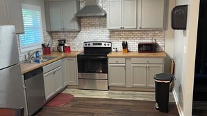 A modern kitchen with white cabinets, a stainless steel dishwasher, a black stove, and a microwave. - RElax, & BeComfortable (Snellville)