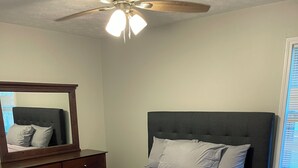 A bedroom with a bed, a ceiling fan, a dresser, and a window with blinds. - RElax, & BeComfortable (Snellville)