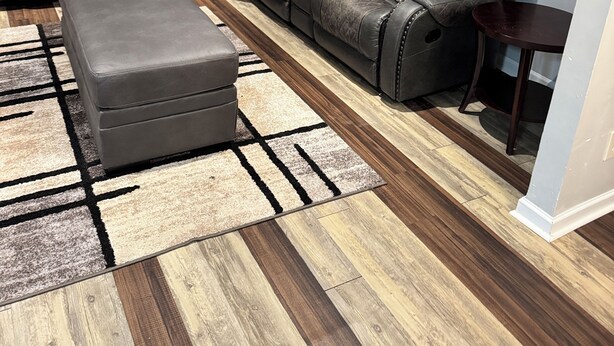A modern living room with a sectional sofa, a grey ottoman, and a wooden floor. - RElax, & BeComfortable (Snellville)