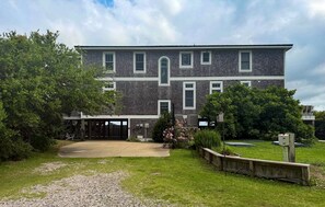 A two-story building with a covered patio, a gravel driveway, and a well-maintained lawn. - Still Point:  Luxurious, spacious, exceptional waterfront home. (Ocracoke)