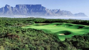 A golf course with a view of mountains in the background. - Manatoka Coastal Condo (Cape Town)