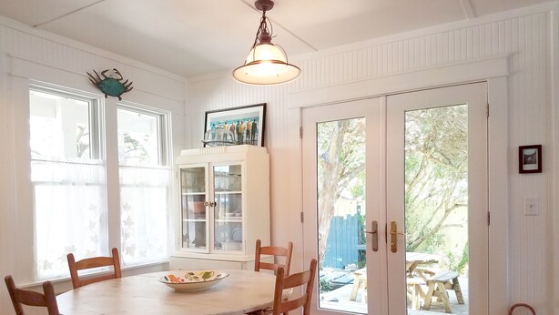 A dining area with a round table, wooden chairs, a cabinet with glass doors, and a wicker basket.