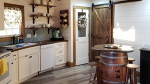 Una cocina con armarios de madera, una estación de café y un barril rústico.