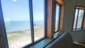 A room with large windows overlooking a beach and the sea. - Soundview:  Dog friendly sound front home, den, private dock. (Ocracoke)
