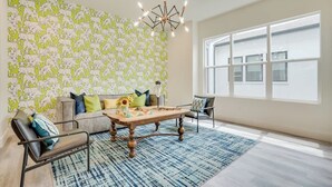A living room with a sofa, coffee table, and a patterned wall. - Funky | Whimsical |Steps from Highland Park (Dallas)