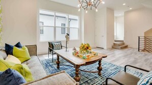 A modern living room with a sofa, coffee table, and a chandelier. - Funky | Whimsical |Steps from Highland Park (Dallas)