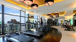 Een moderne sportschool met loopbanden, elliptische trainers en gewichten. Grote ramen bieden uitzicht over de stad.