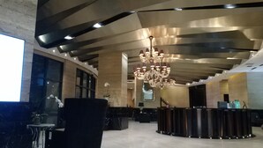 Een moderne lobby met een receptiebalie, een kroonluchter en een marmeren vloer.