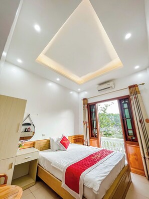 A bedroom with a bed, bedside table, and a desk with a mirror. - Hong Ngoc Hotel (Yen Bai)