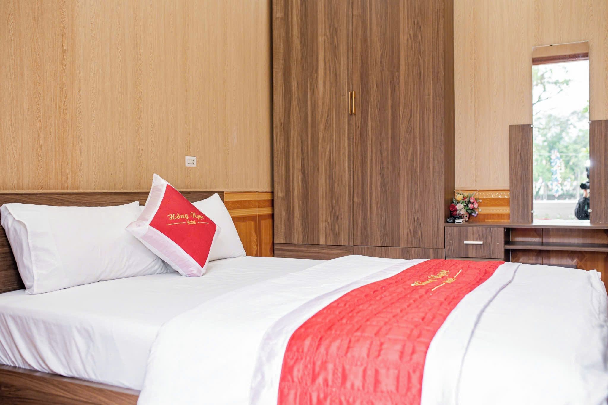 A hotel room with a bed, a nightstand, a mirror, and a window.