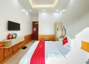 A hotel room with a bed, a TV, a desk, a chair, a wardrobe, and a mirror. - Hong Ngoc Hotel (Yen Bai)