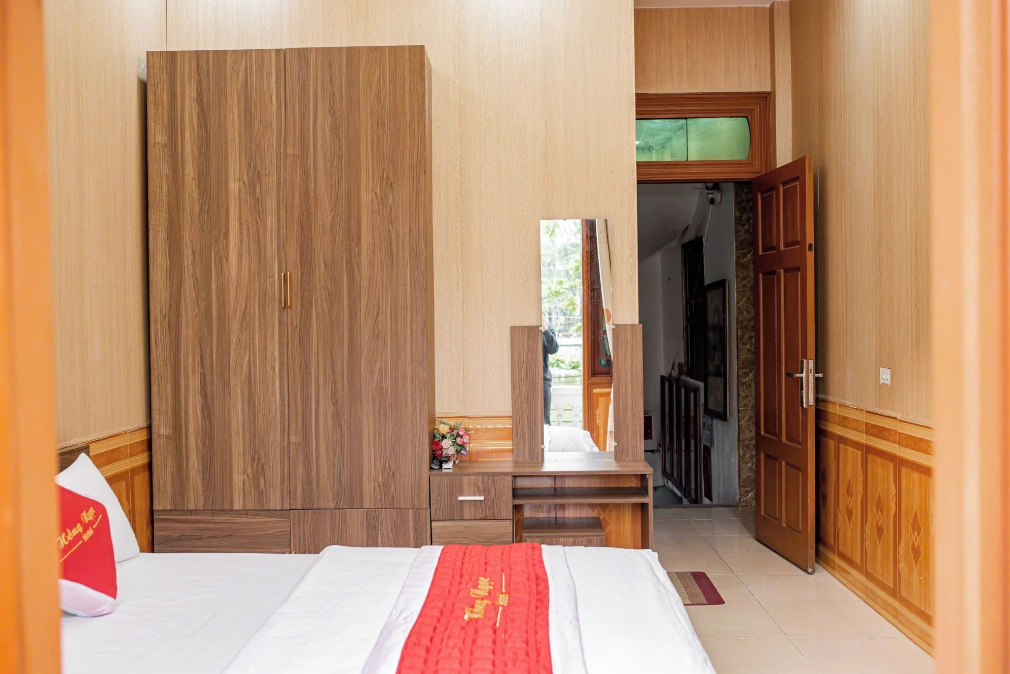 Een hotelkamer met een bed, een bureau, een kledingkast en een badkamer, zichtbaar door een geopende deur.