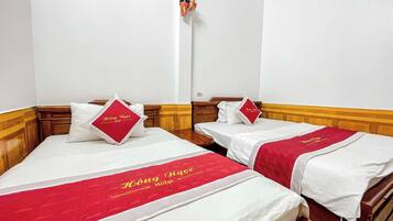 Dos camas individuales con ropa de cama roja y blanca, cabeceros de madera y una pared blanca con un interruptor de luz.