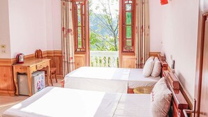 A room with two beds, a wooden desk, a kettle, and a small refrigerator. - Hong Ngoc Hotel (Yen Bai)
