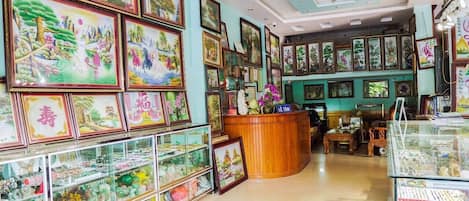 A room with a wooden reception desk, framed artwork on the walls, and glass display cases with various items.