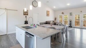 A spacious kitchen with a central island, a dining area with a table and chairs, and a ceiling fan.