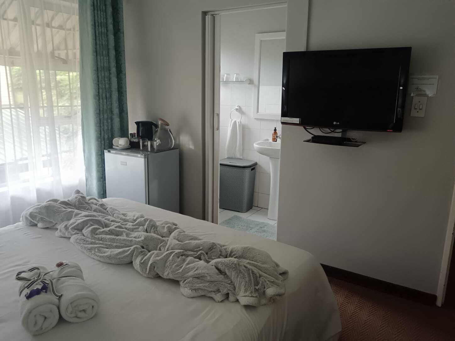 Een hotelkamer met een bed, een televisie, een klein kitchenette en een badkamer die door een geopende deur zichtbaar is.