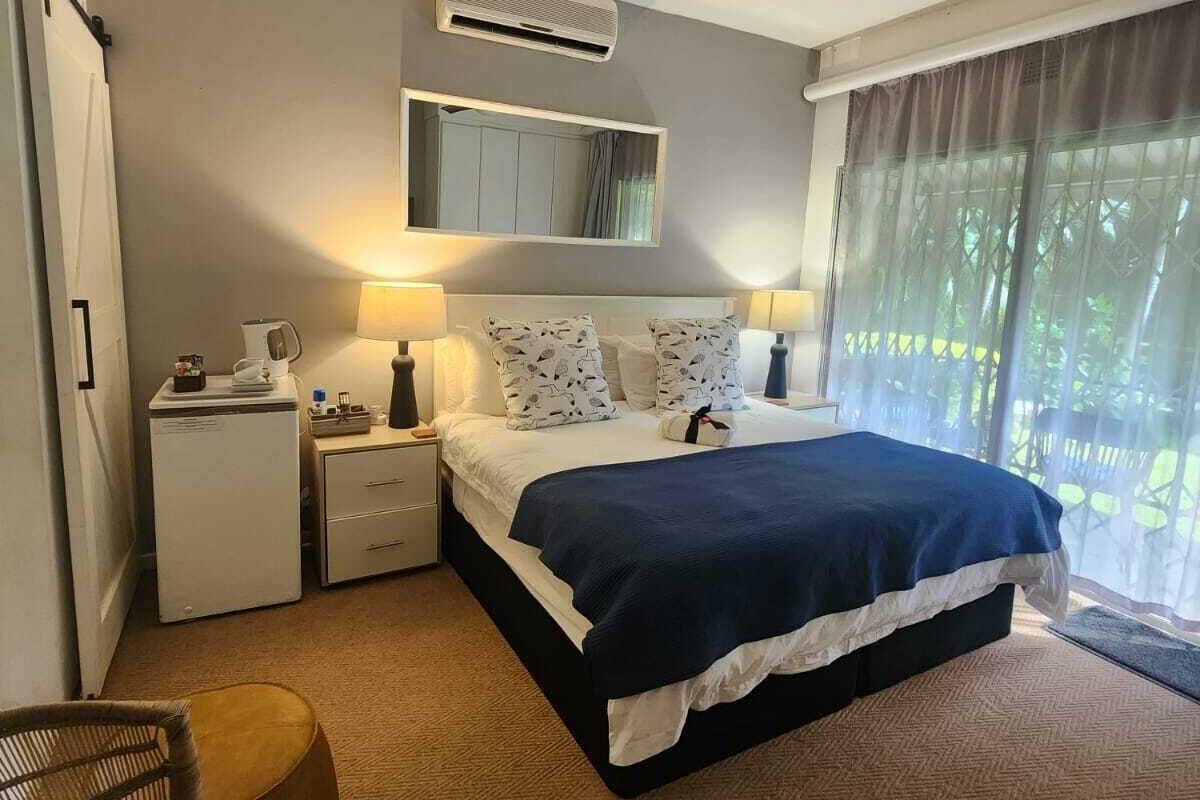 A bedroom with a bed, bedside tables, a chair, a ceiling fan, and a window with curtains.