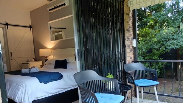 A modern hotel room with a bed, bedside tables, a desk, and a chair. - Hillton Manor Guest House (Richards Bay)