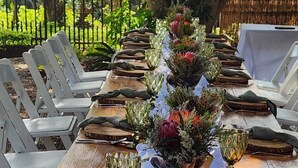 A long wooden table set with glassware, cutlery, and floral centerpieces. - Hillton Manor Guest House (Richards Bay)